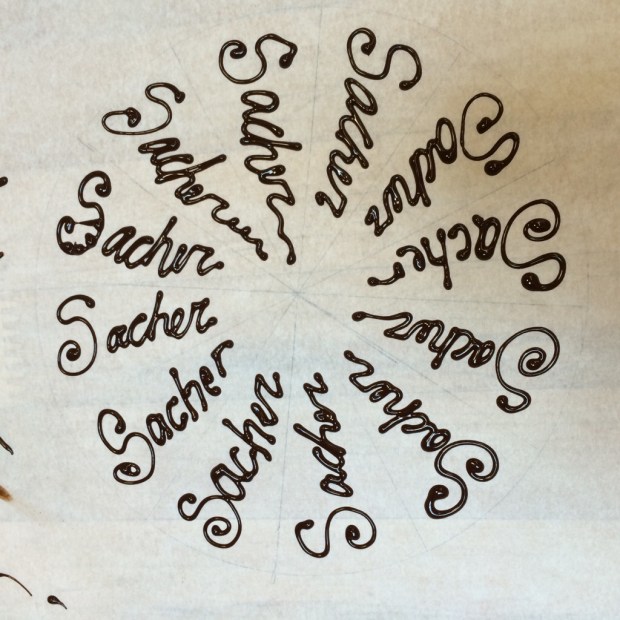 Practicing chocolate writing on  parchment paper before writing on the cake.